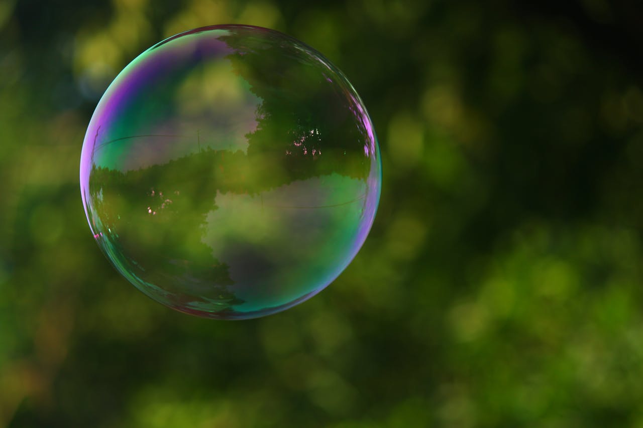 Colorful soap bubble reflecting nature in a park setting with a blurred green background.